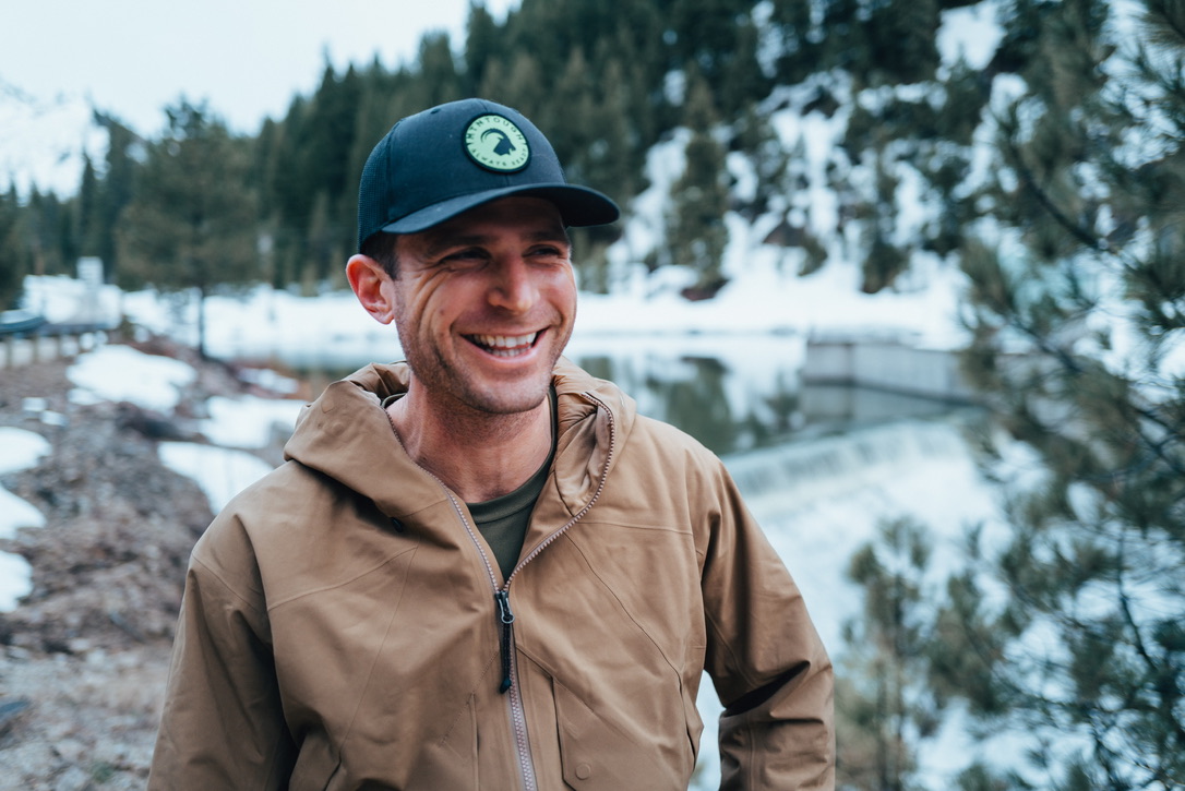 Kyle Layne smiling outdoors beside a snowy mountain lake.